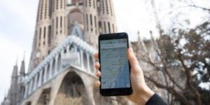 Un usuari utilitzant una aplicaci&oacute; d'una empresa de cotxes amb llic&egrave;ncies VTC davant de la Sagrada Fam&iacute;lia